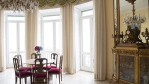 Un coin repas avec une table ronde, quatre chaises et un vase rempli de fleurs.