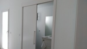 A hallway with a closed door, a sliding door, and a bathroom with a sink and mirror. - QUINTERO SUITES (NOPAL AND VEROL) 2 COUPLES? BOOK THE TWO SUITES (San Bartolomé)