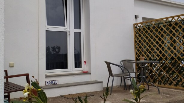A white building with a window, a wooden bench, a table with chairs, and a sign reading "NOPAL". - QUINTERO SUITES (NOPAL AND VEROL) 2 COUPLES? BOOK THE TWO SUITES (San Bartolomé)