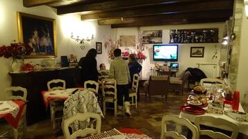 Ein gemütlicher Essbereich mit Holzbalken, einem Fernseher und einer Bar.