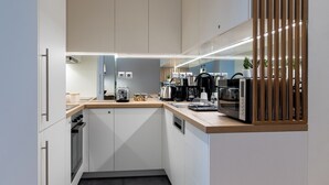 Una cocina moderna con armarios blancos, encimera de madera y varios electrodomésticos, como cafetera, tostadora y microondas.