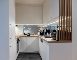 A modern kitchen with white cabinets, a wooden countertop, and a built-in microwave.