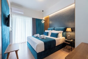 Une chambre d’hôtel moderne équipée d’un grand lit, d’un téléviseur à écran plat, d’un bureau et d’une lampe.