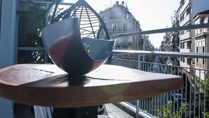 Un balcón con una mesa, una silla colgante y vistas a edificios en el fondo.