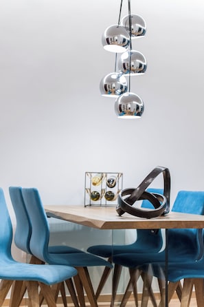 A dining area with a wooden table, blue chairs, and a unique spherical pendant light.