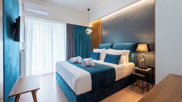 Una habitación de hotel moderna con una cama grande, un televisor de pantalla plana, un escritorio y una lámpara.