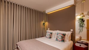 A hotel room with a large bed, a bedside table, a red nightstand, and a wall-mounted plant. - High Classe One Bedroom Apt for 3 - River View 3 (Vila Nova de Gaia)