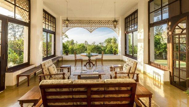 Una habitación amplia con una gran mesa de comedor, varias sillas y vistas al exterior con vegetación.