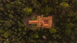 Vista aérea de un edificio cuadrado con un patio central, rodeado de un bosque denso.
