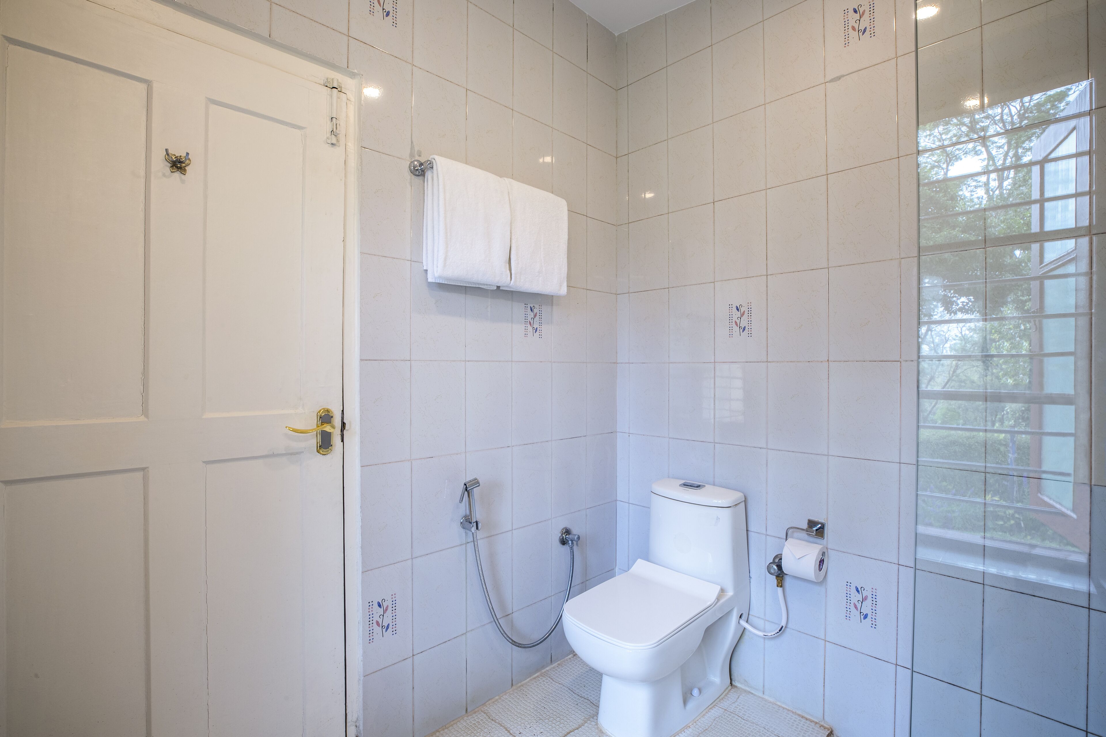A small, white bathroom with a toilet, a shower, and a towel rack.