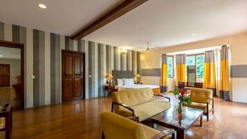 A hotel room with a bed, a sofa, a dining table, and a window with curtains.