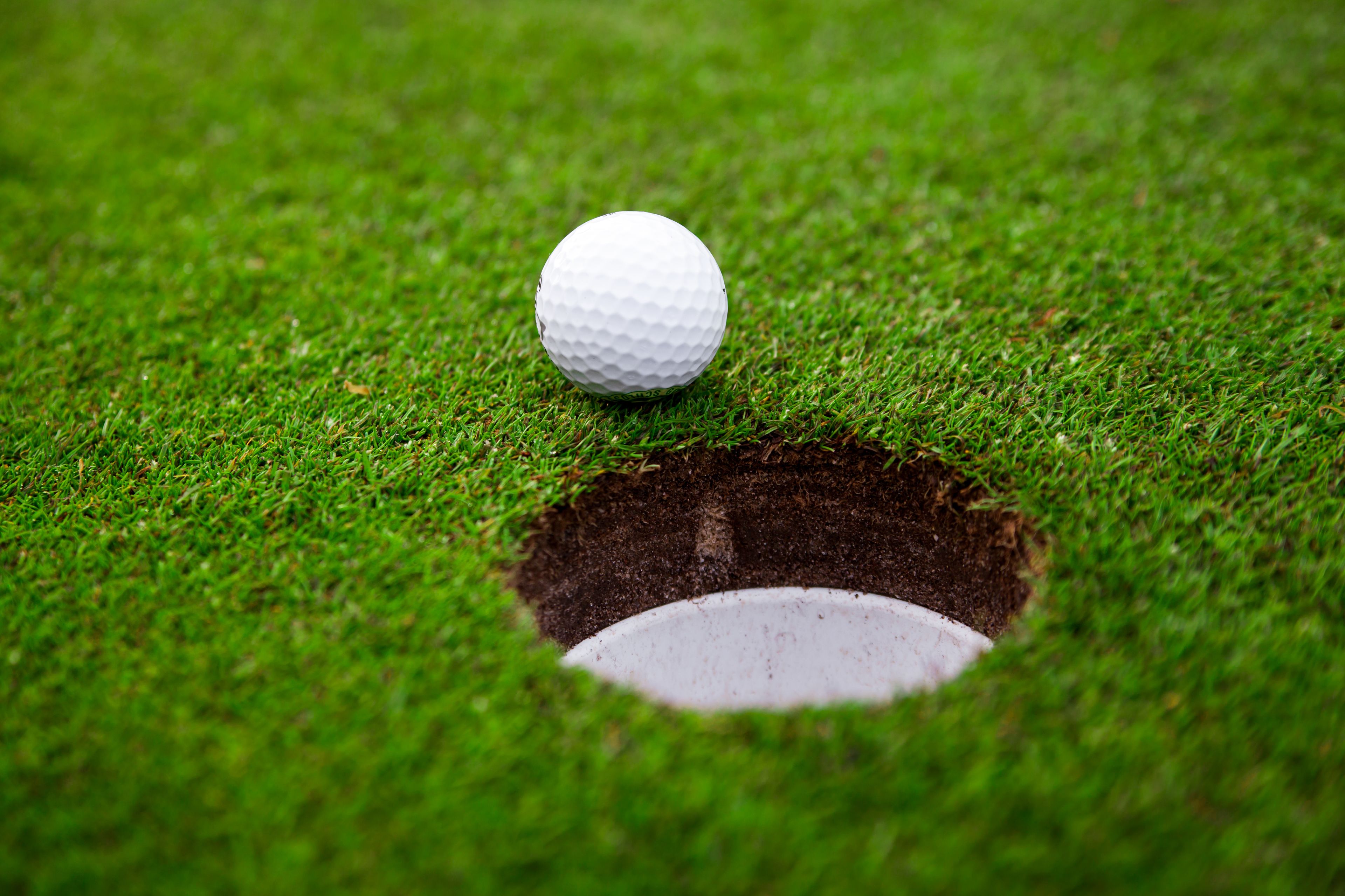 Una pelota de golf sobre un campo verde con un hoyo.