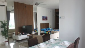 A modern hotel room with a dining area, a TV, a bed with a colorful headboard, and a ceiling fan. - Studio At Mansion One (George Town)