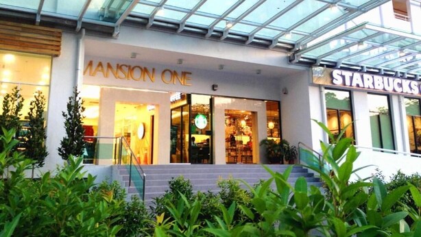 A building with a glass facade, a Starbucks, and a store named 'Mansion One'. - Studio At Mansion One (George Town)