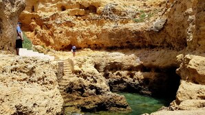 A rocky terrain with a water stream and steps leading into a cave. - Albufeira, with terrace, sea views, 5 min to beach (21) (Albufeira)