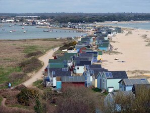 A coastal area with beach houses, a sandy beach, and boats in the water. -   LUXURY 1 BED  FLAT  WITH GARDEN & PARKING - 2 MINS WALK TO RIVER  DOG FRIENDLY (Bournemouth)