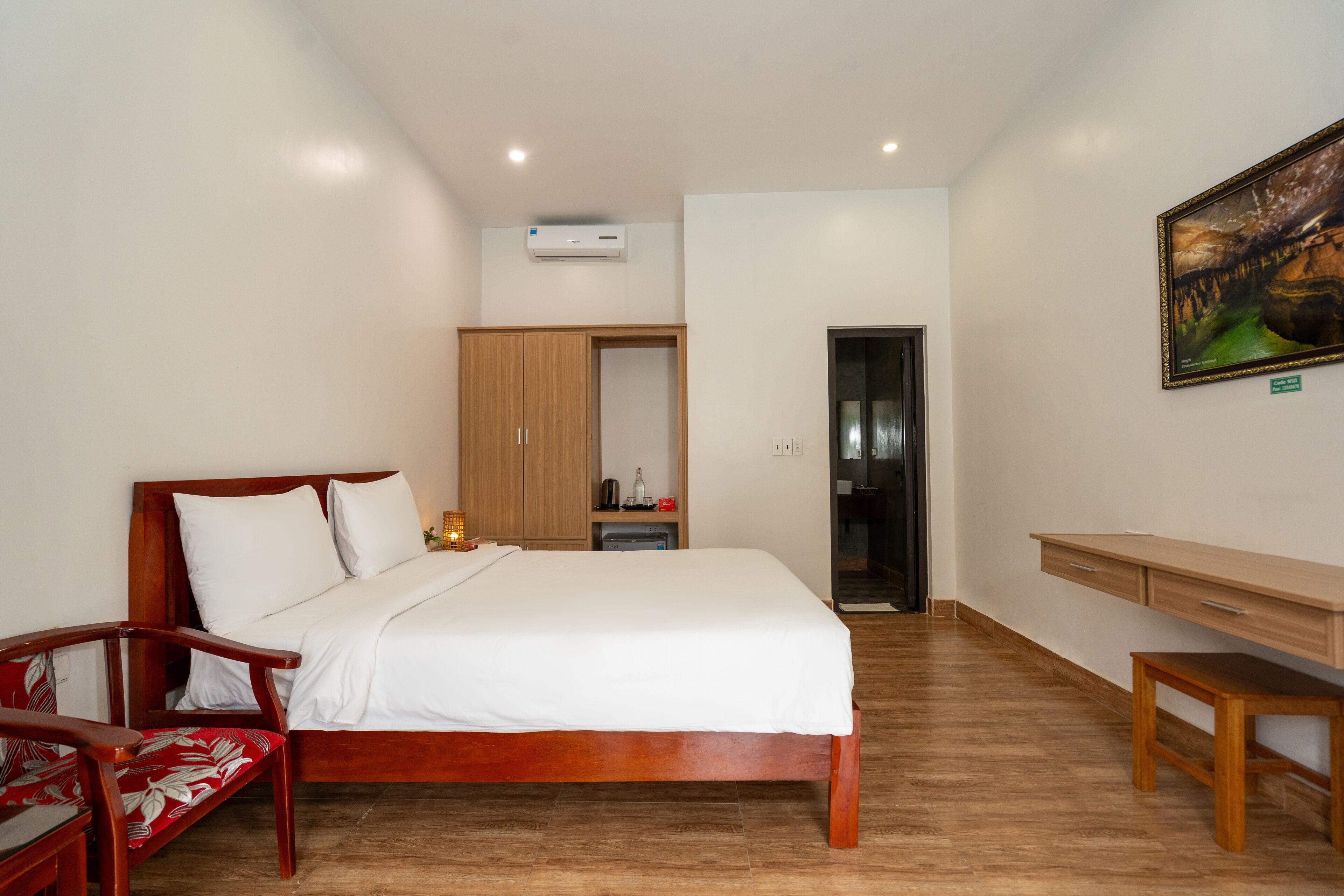 Une chambre d’hôtel avec un lit en bois, un bureau en bois, une chaise et une armoire.