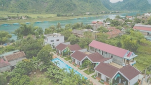 A residential area with houses, a swimming pool, and a river with boats. - Commander Lodge (Phong Nha)