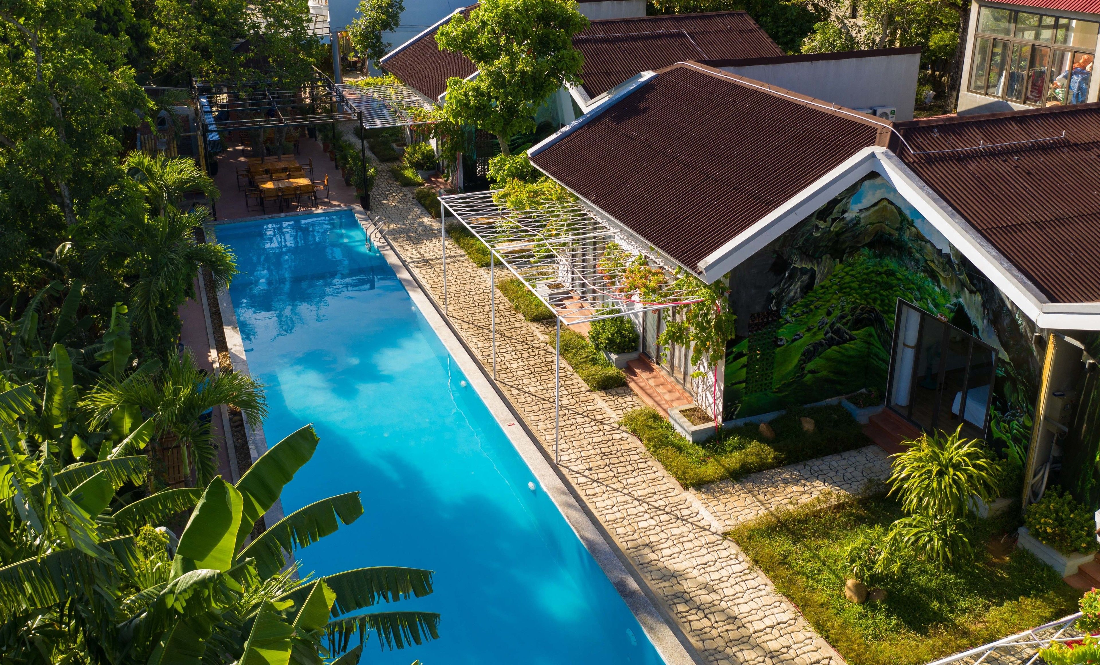A swimming pool surrounded by lush greenery and a covered outdoor seating area.
