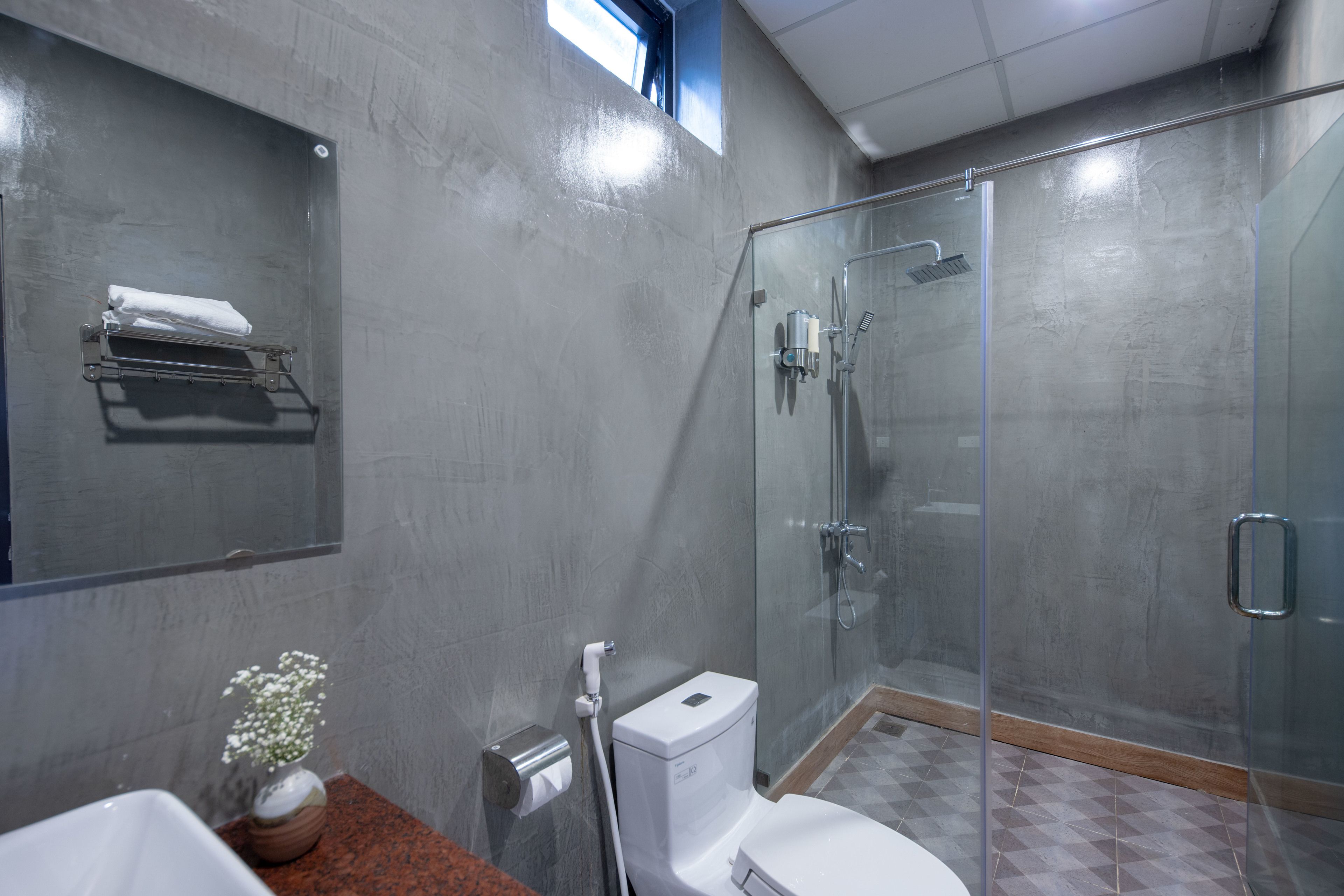A modern bathroom with a glass-enclosed shower, a toilet, and a sink.