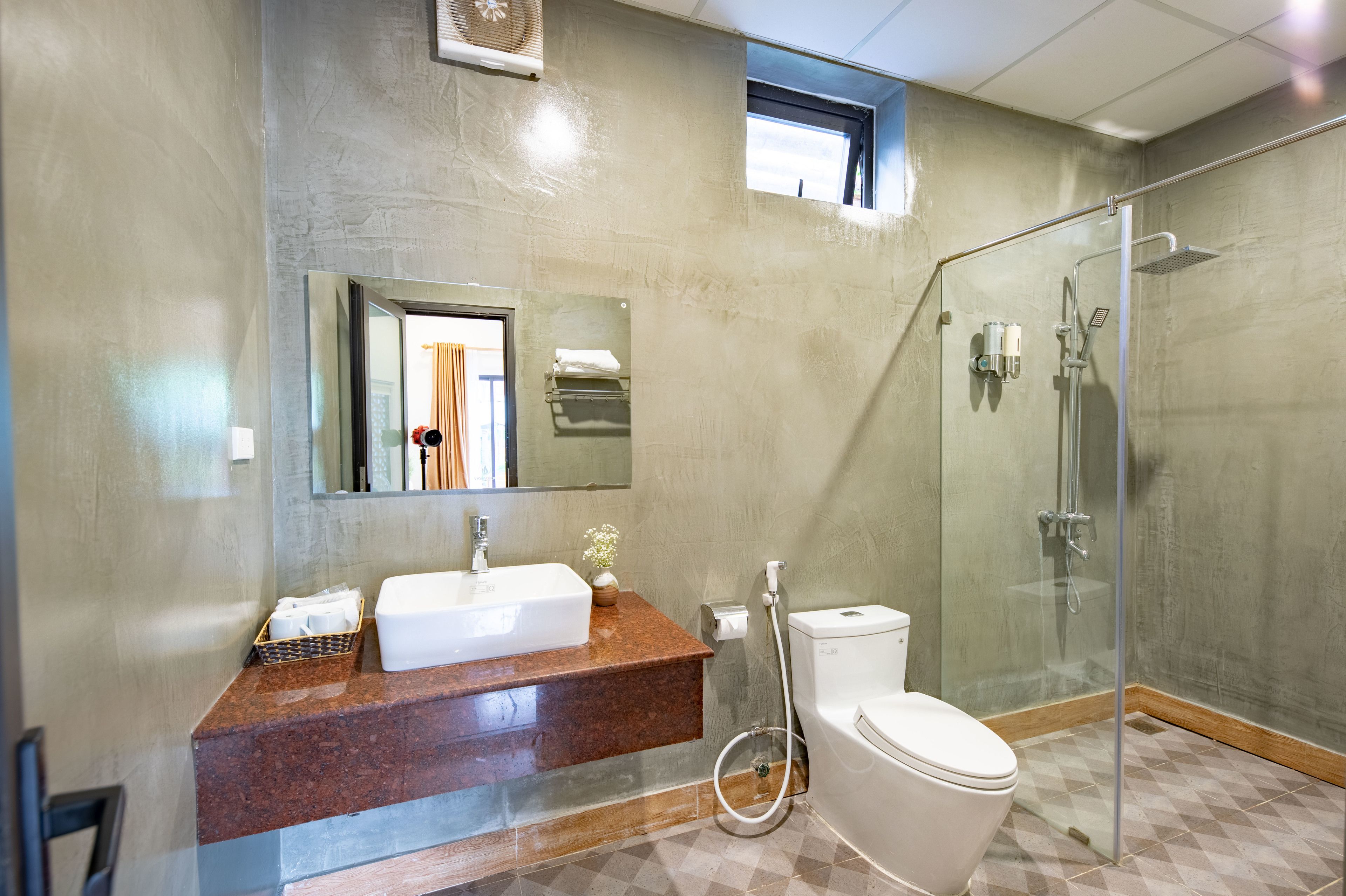 A modern bathroom with a glass-enclosed shower, a white sink, and a toilet.