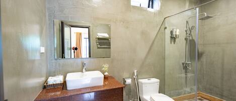 A modern bathroom with a glass-enclosed shower, a white sink, and a toilet.