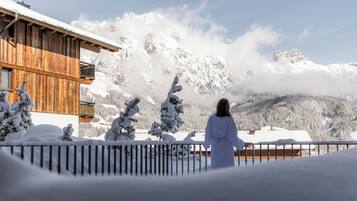 A wooden cabin with a balcony overlooking a snowy mountain landscape.