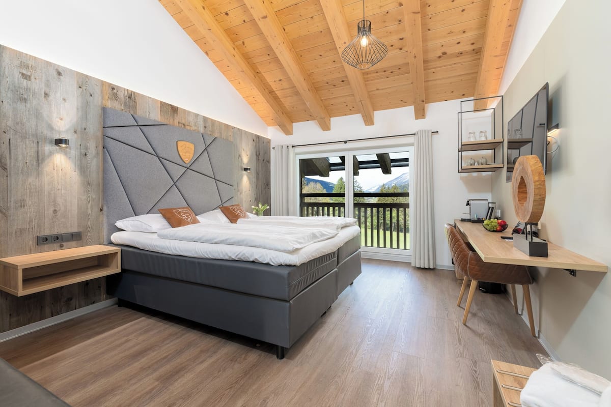 Ein modernes Schlafzimmer mit einem großen Bett, Holzboden und Bergblick durch die Schiebetüren.