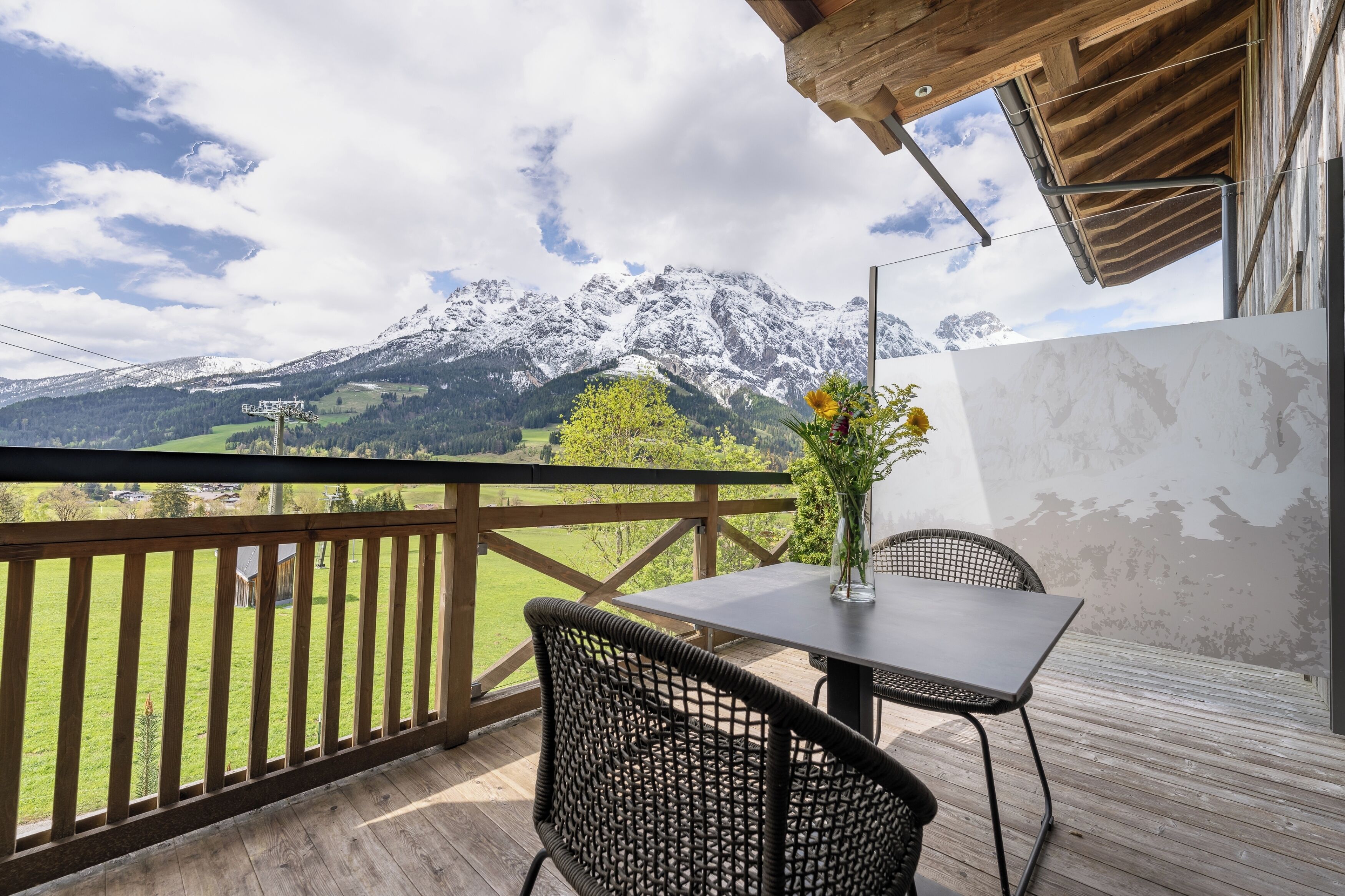 Un balcón con una mesa y sillas, con vistas a un paisaje montañoso.