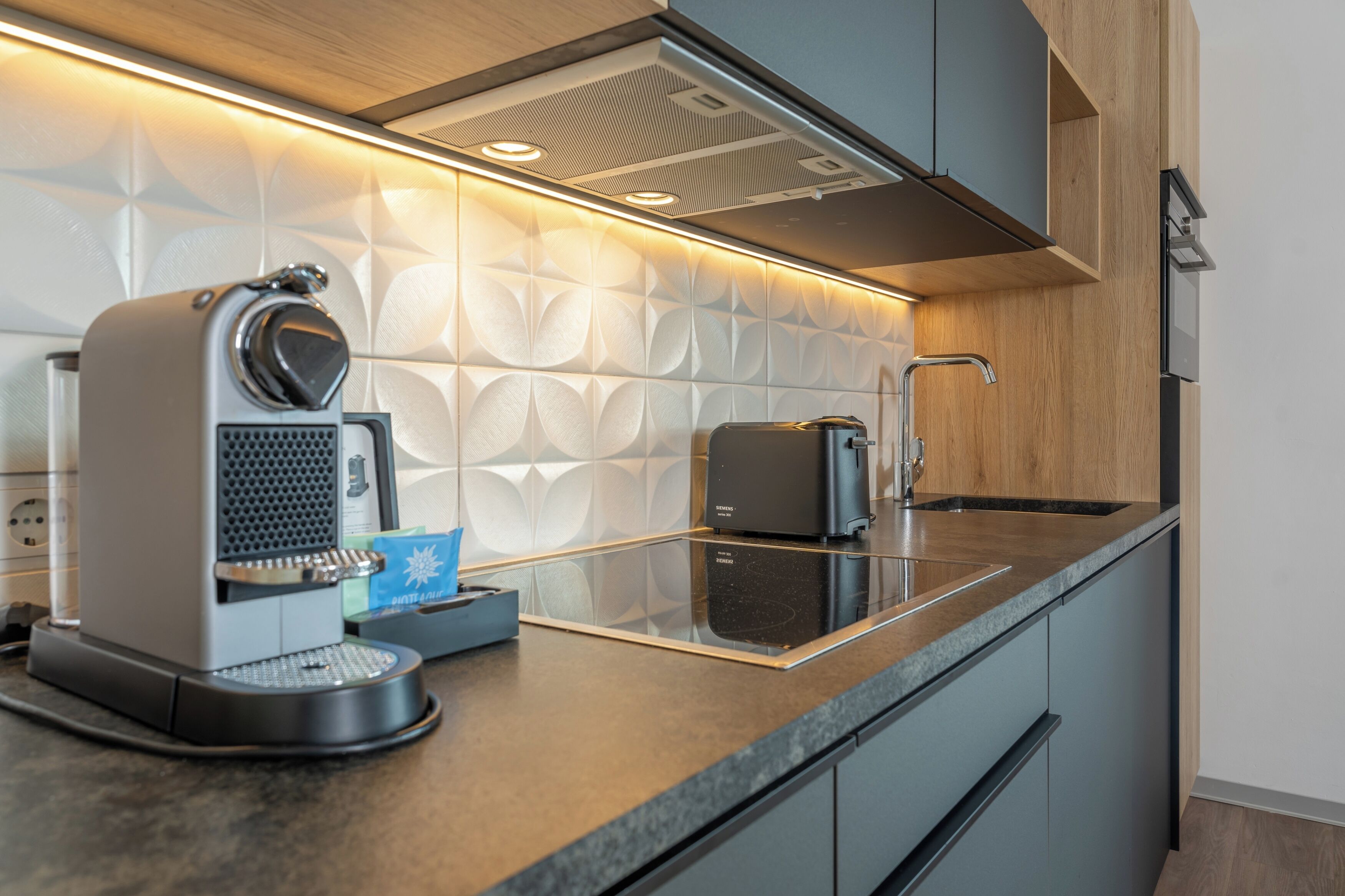 A modern kitchen with a coffee machine, a toaster, and a sink.