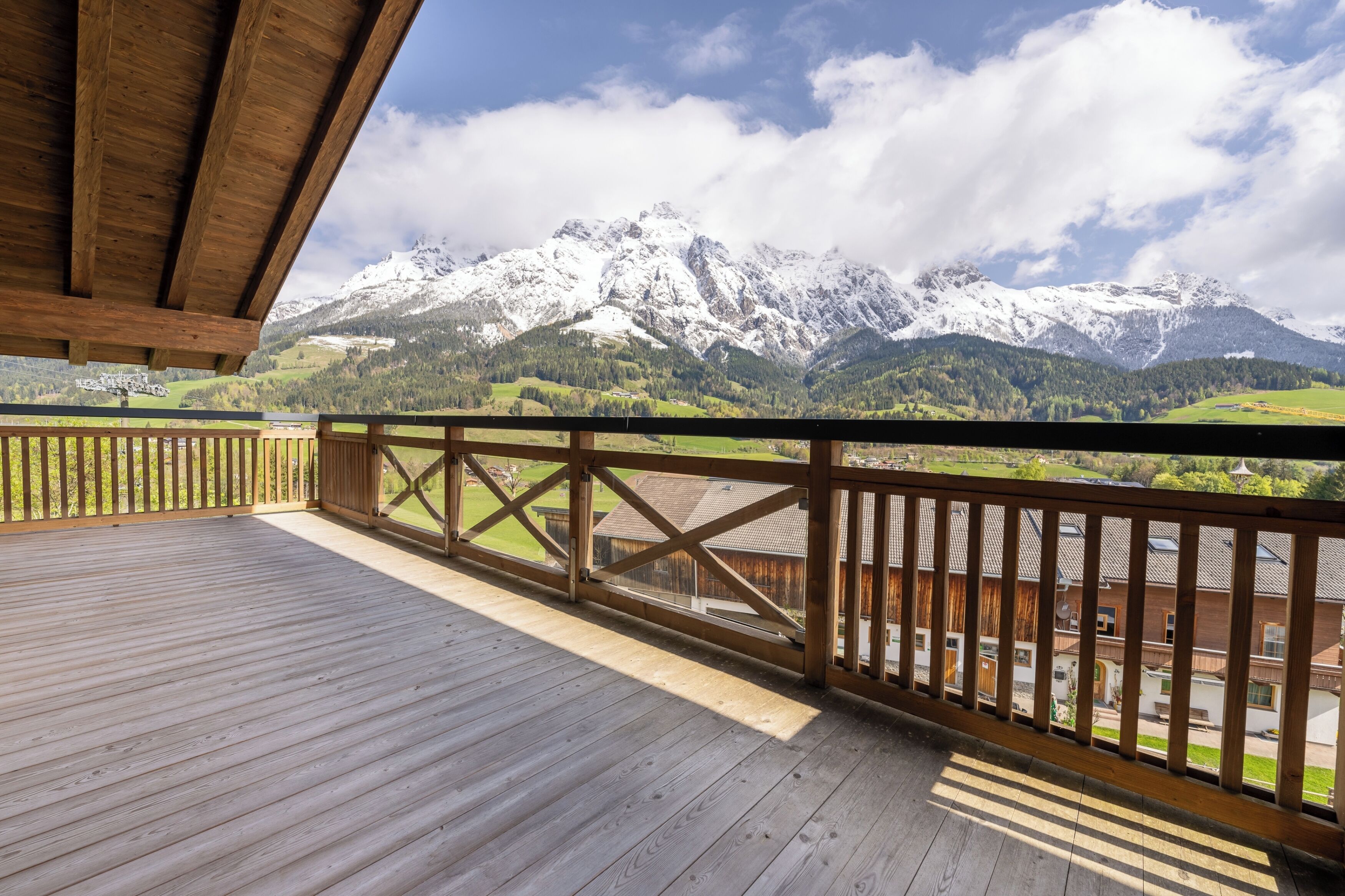 A wooden deck with a view of snow-capped mountains and a clear sky.