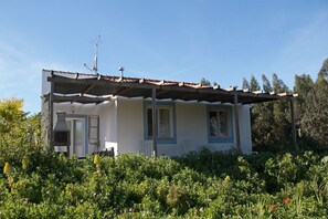 A single-story house with a covered porch, a chimney, and a garden in front. - Adults Only - Monte Horizonte Casa Sobreiro Eco & Nature (Santiago do Cacém)