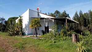 Une maison de plain-pied, avec une façade blanche, un toit recouvert de tuiles rouges et une antenne parabolique sur le toit.