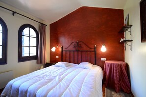 A bedroom with a large bed, two bedside lamps, a small table with a red tablecloth, and a window with curtains. - PASSATGE BERNA, 2 (Estartit)