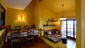 Uma sala de jantar com mesa posta para quatro, um sofá e uma mesinha de centro com abajur.
