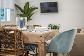 A dining area with a wooden table, wicker chairs, and a blue upholstered chair. - Zurbano I- Ideal accommodation in the heart of Calle Zurbano (Madrid)