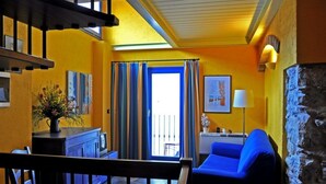 A room with a blue sofa, a small table with a vase, a staircase, and a view of the outside. - Agriturismo Ca' dei Conti (San Bartolomeo al Mare)