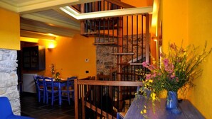 A dining area with a wooden staircase, a stone wall, and a blue sofa. - Agriturismo Ca' dei Conti (San Bartolomeo al Mare)