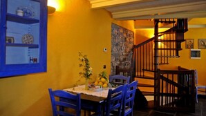 A dining area with a table set for two, a blue chair, and a wooden staircase leading to an upper level. - Agriturismo Ca' dei Conti (San Bartolomeo al Mare)