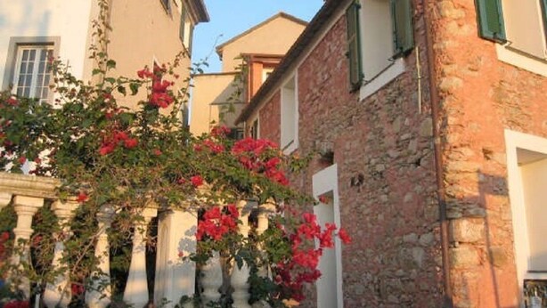 A narrow street with buildings featuring stone facades and green shutters. - Agriturismo Ca' dei Conti (San Bartolomeo al Mare)