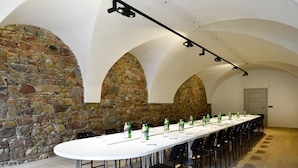 A conference room with a long table, stone walls, and arched ceilings. - Garden Rooms (Maribor)