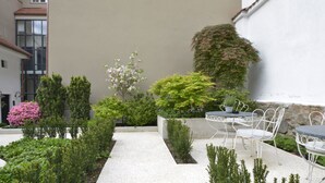 A courtyard with a white building, a gravel path, and a table with chairs. - Garden Rooms (Maribor)