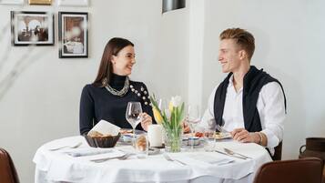 A dining table with a white tablecloth, plates, cutlery, and a vase with flowers.