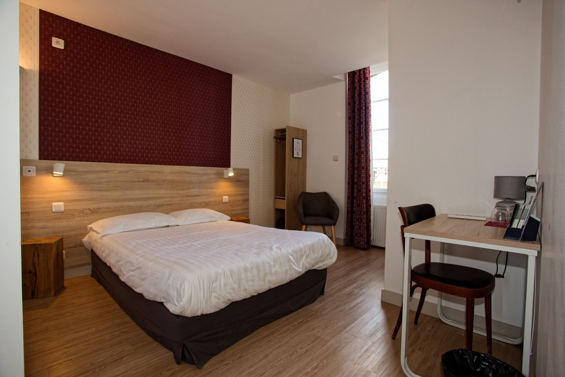 A hotel room with a bed, a desk, and a chair.