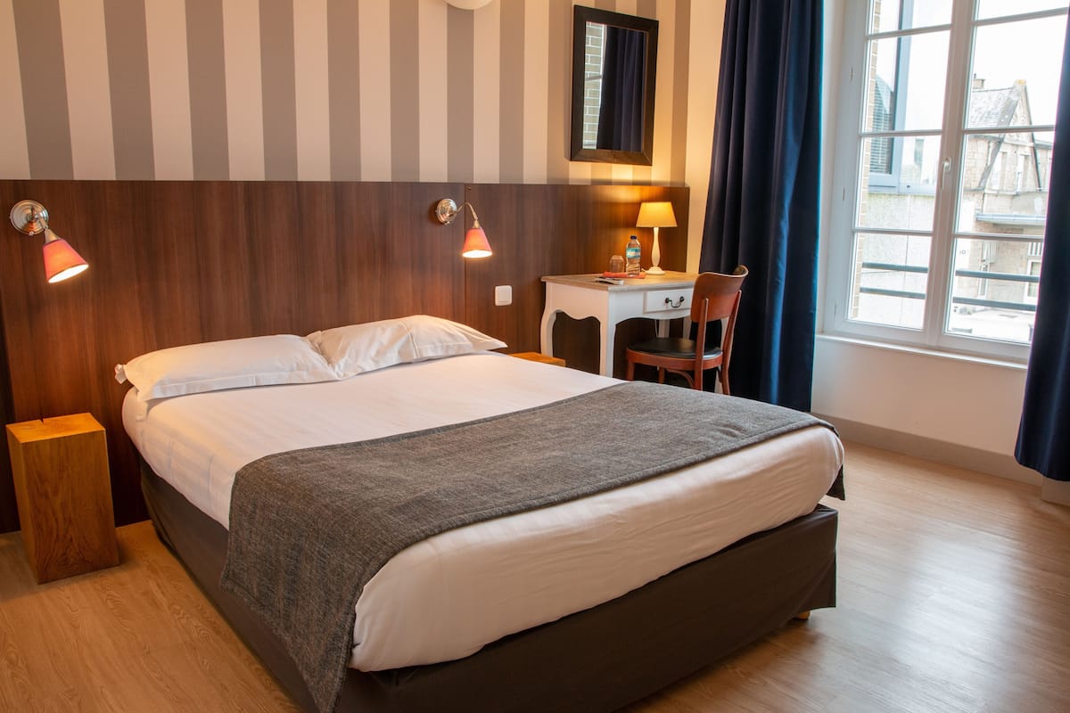 Ein Hotelzimmer mit Bett, Nachttischlampen, Schreibtisch und Stuhl.