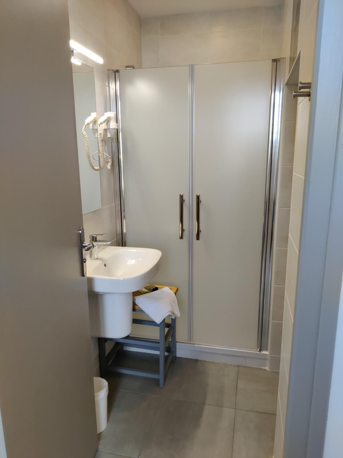 Une salle de bain moderne avec un lavabo blanc, un miroir et une douche à parois de verre.