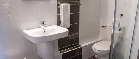 A modern bathroom with a white sink, a glass shower enclosure, and a toilet.