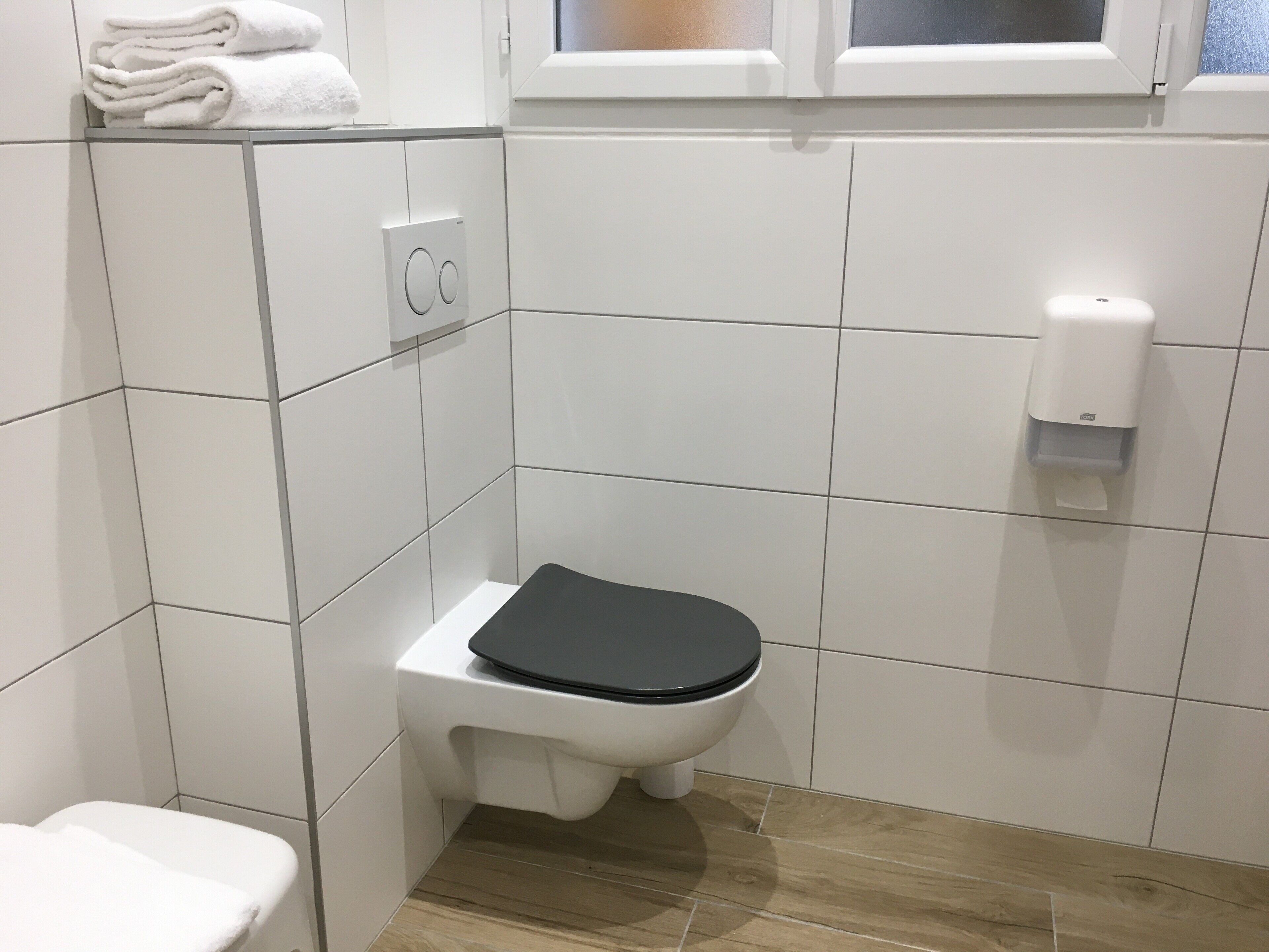 A small, modern bathroom with a toilet, a hand dryer, and a towel rack.