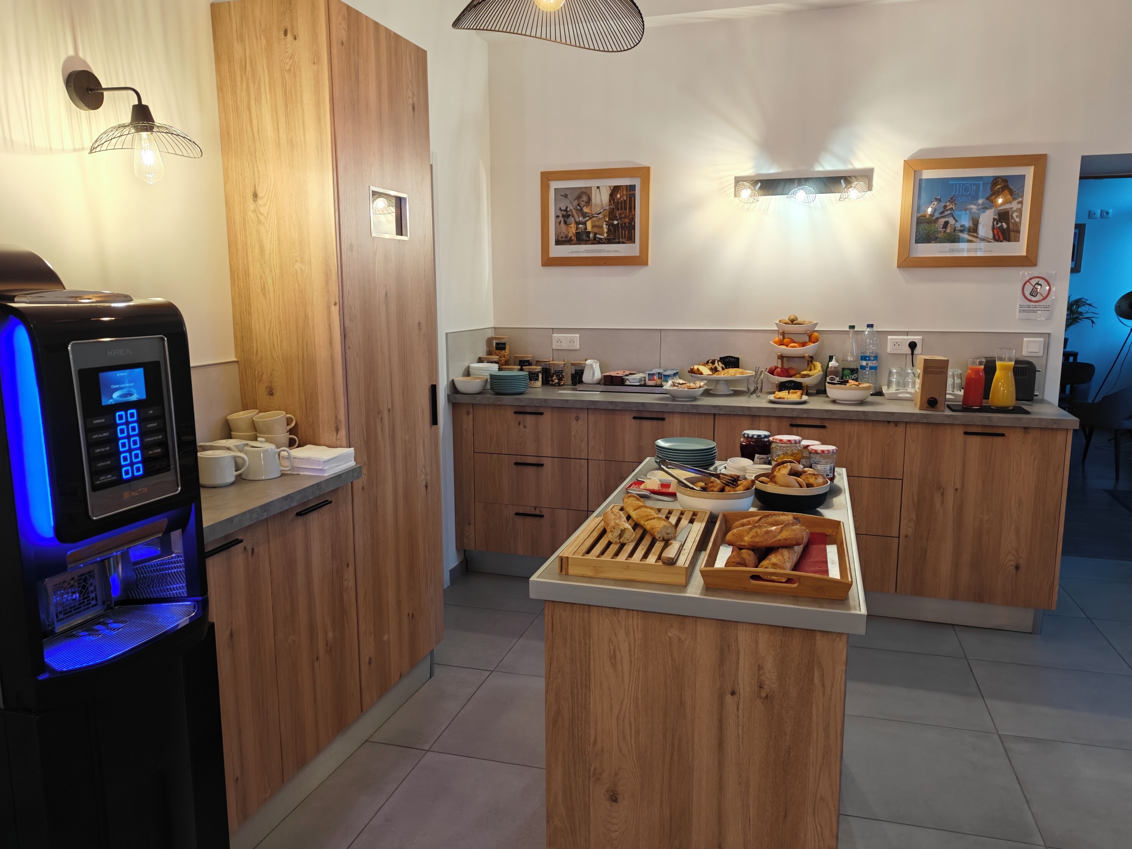 A modern kitchen with wooden cabinets, a coffee machine, and a breakfast buffet.