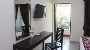 Une chambre d’hôtel avec un lit, un bureau et une chaise, une télévision et une fenêtre avec des rideaux.